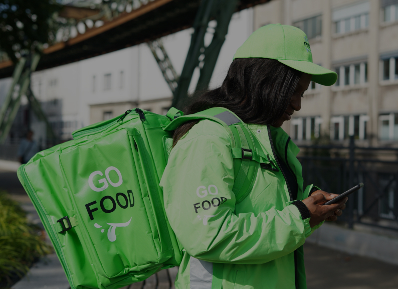 Female delivery agent carrying a green bag and putting on a green cap